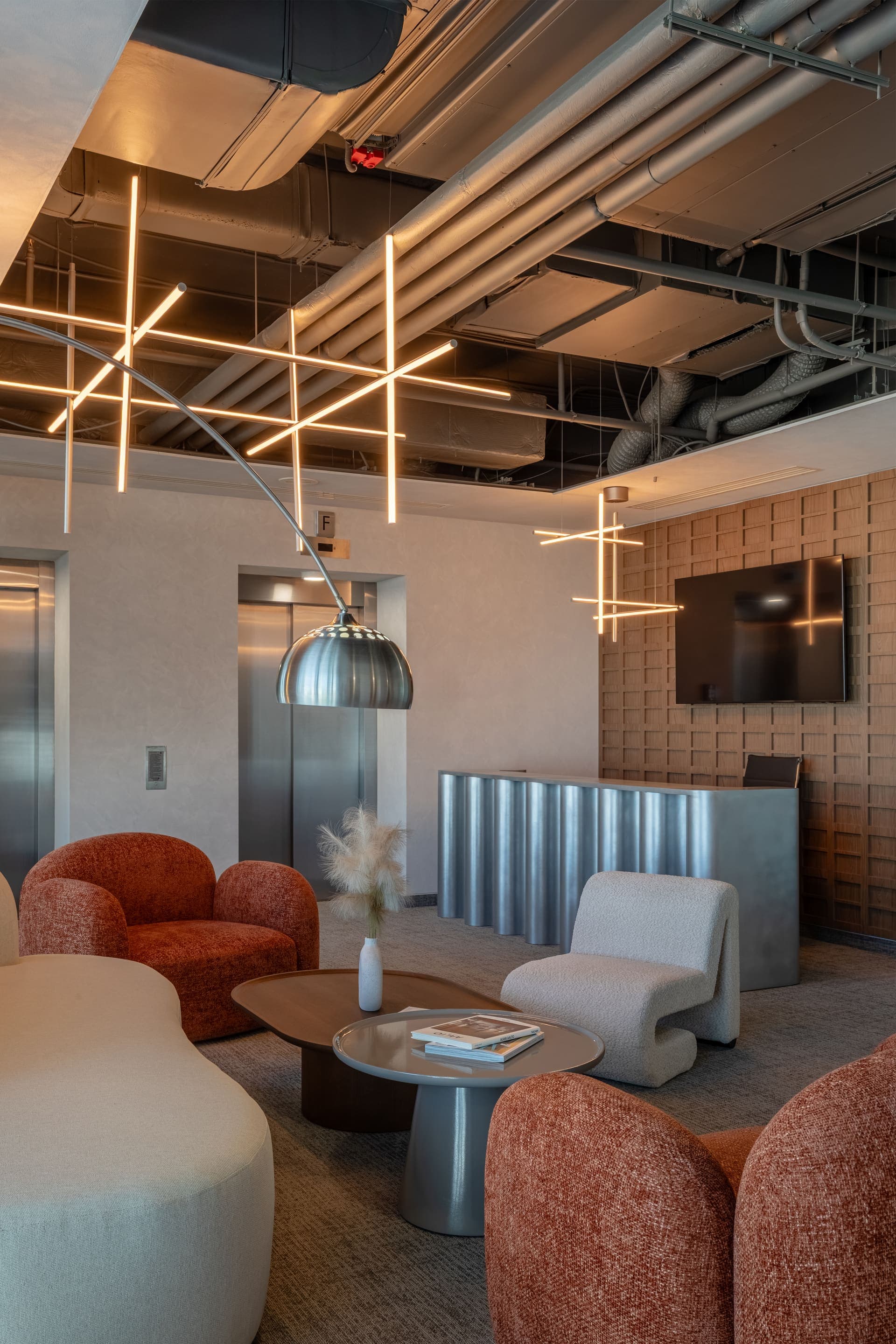 Lounge with rust armchairs and a cream sofa before the ADREM logo wall